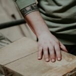 a person with their hand on a piece of wood